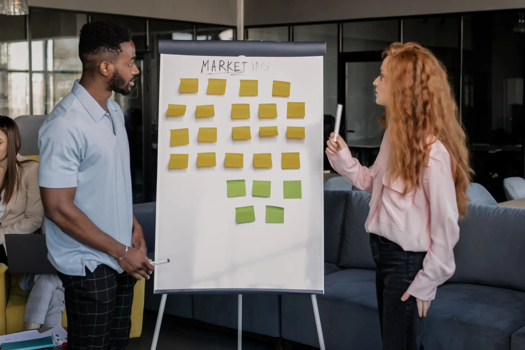 Two colleagues reviewing a marketing board covered in sticky notes