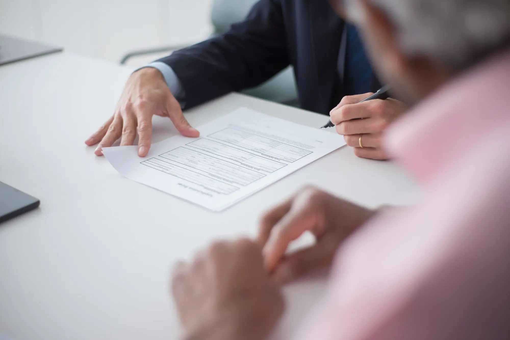Client signing documents with an advisor at a table
