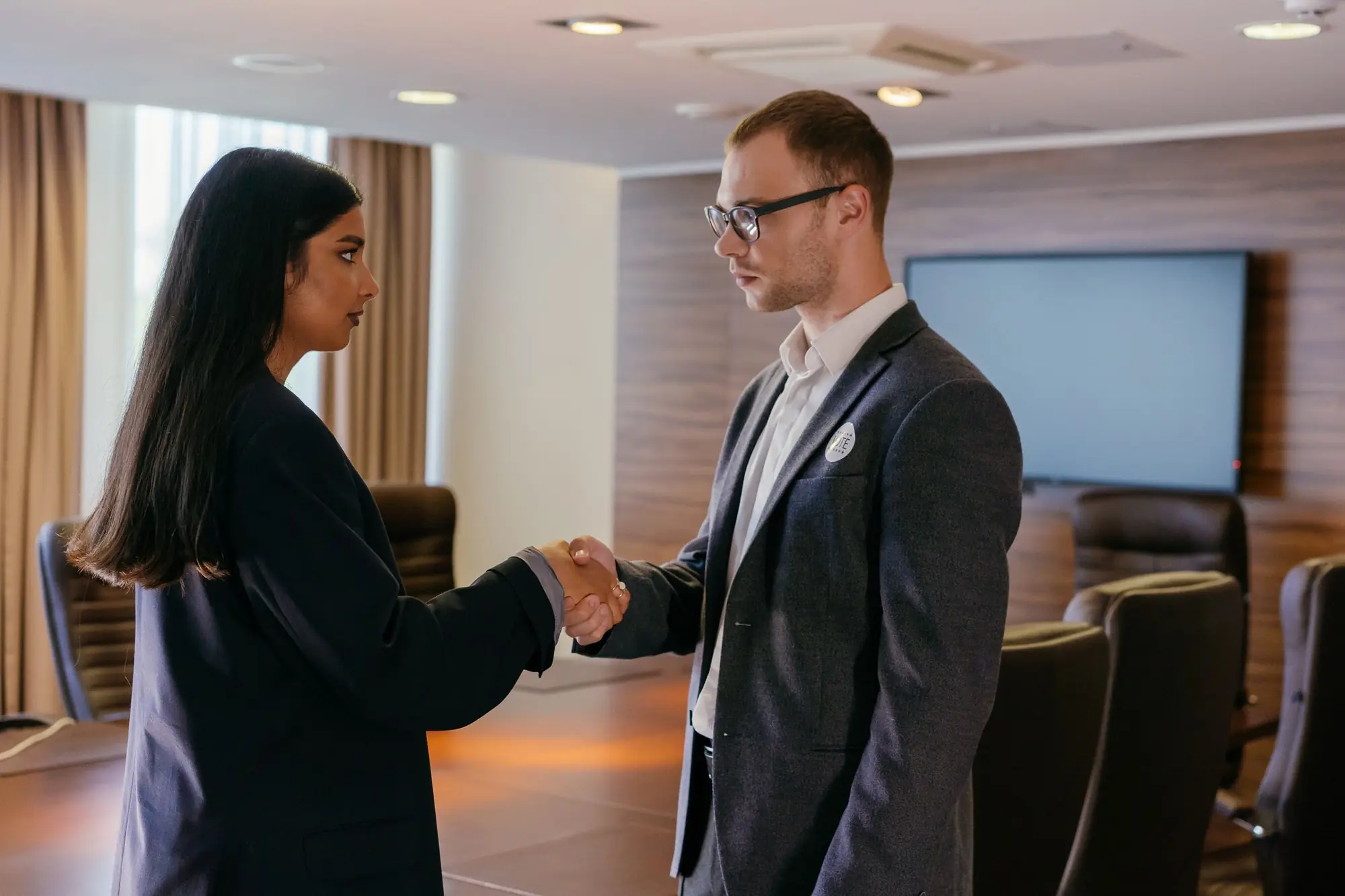Two professionals shaking hands in a meeting room